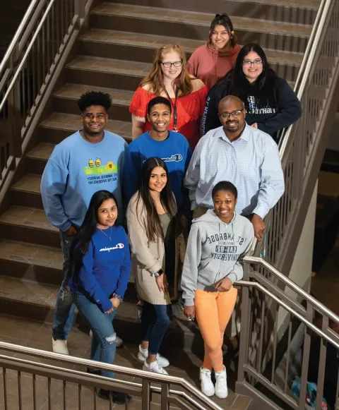 Student leaders in DEI initiatives standing on staircase together, smiling for photo.